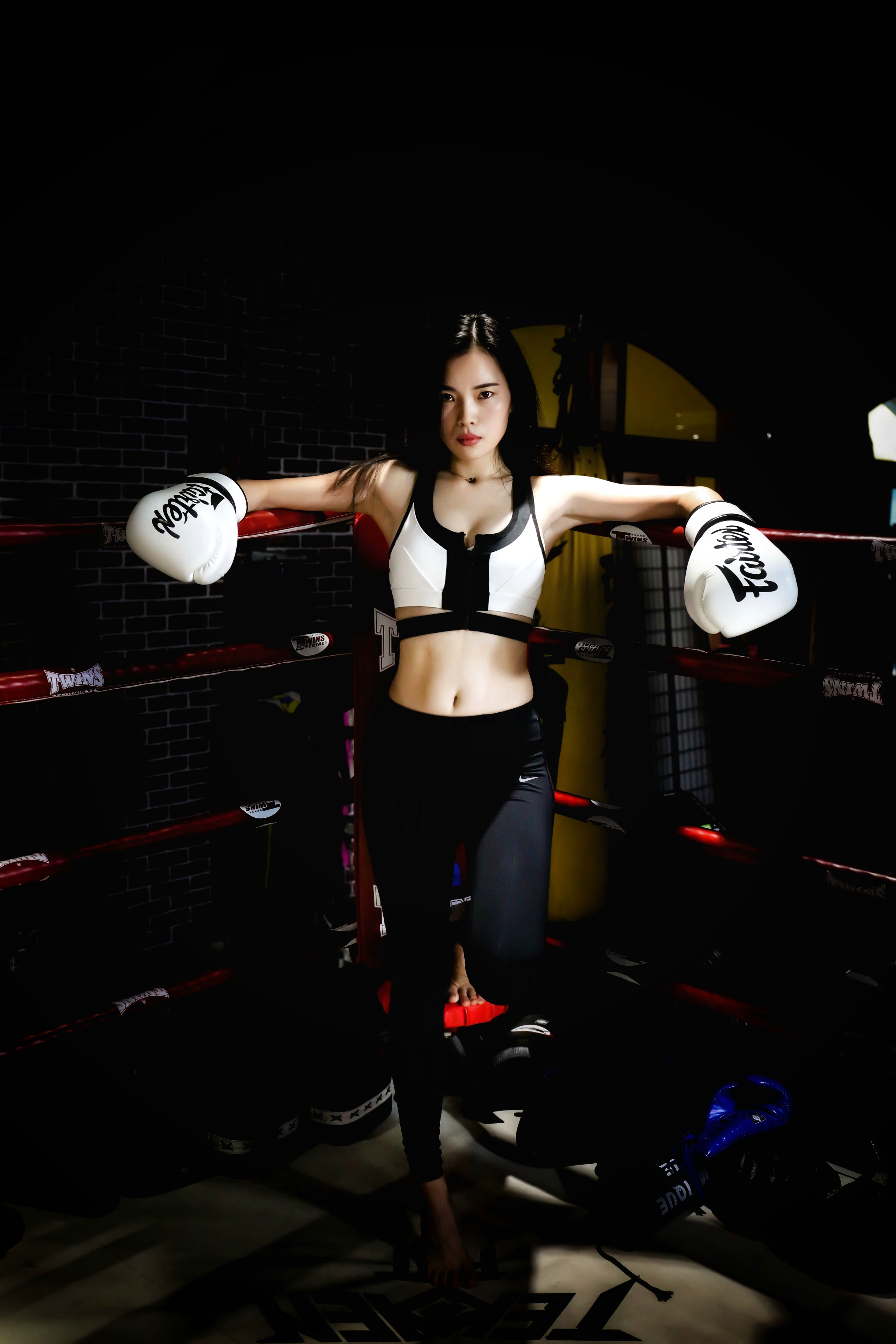 Selbstdisziplin – Frau, schwarz-weiß gekleidet, mit Boxhandschuhen lehnt in einem Boxring